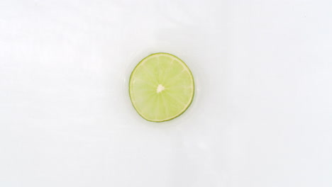 Splashes-of-water-fall-on-sliced-lime-green-rings-on-a-white-background.-Super-slow-motion.